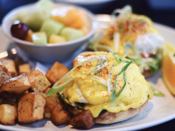 Eggs Benedict with roasted potatoes and a fruit salad